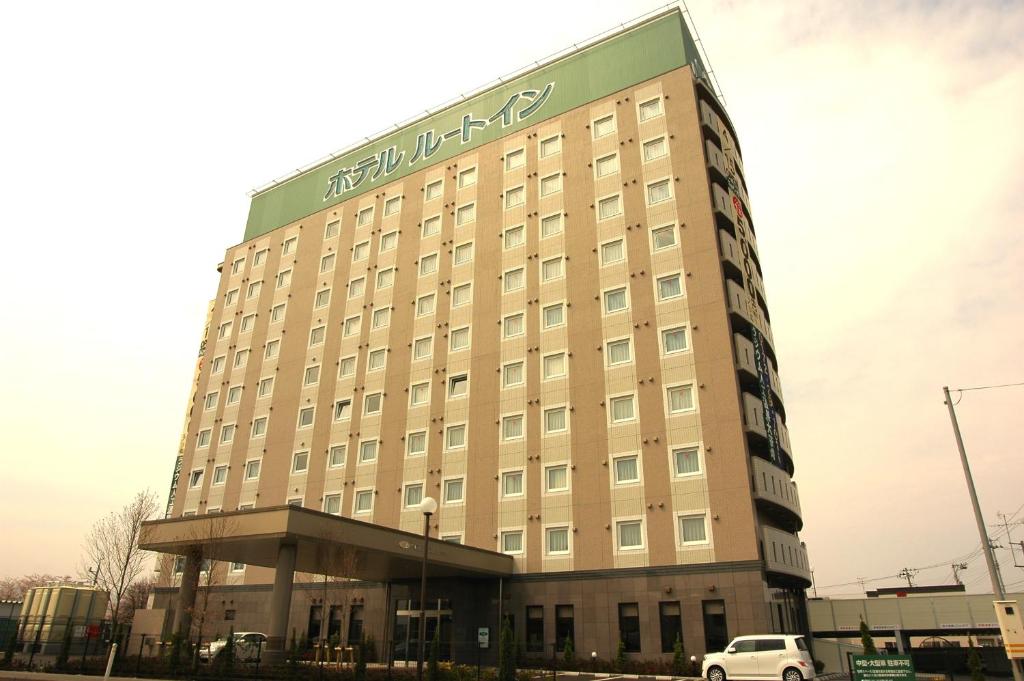 Hotel Route-Inn Hirosaki Joto في هيروساكي: مبنى الفندق مع وجود سيارة متوقفة أمامه