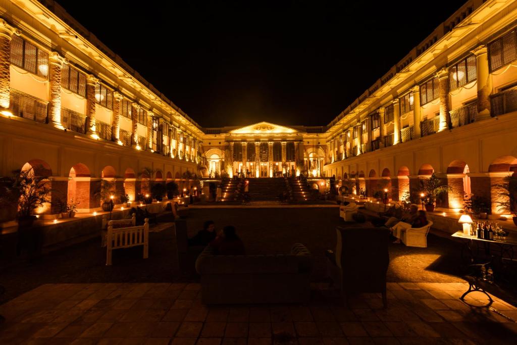 a building with people sitting in the courtyard at night at The Rajbari Bawali in Kolkata