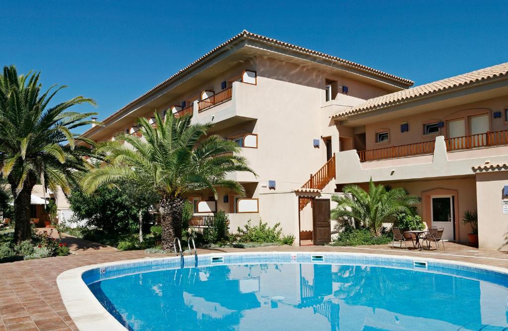 a villa with a swimming pool in front of a house at Hotel Voramar - Emar Hotels in Es Pujols