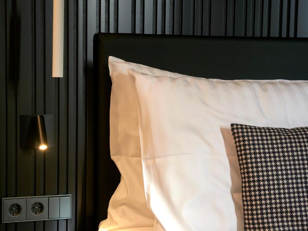a bed with a white pillow and a black headboard at Hostellerie Stafelter in Walferdange