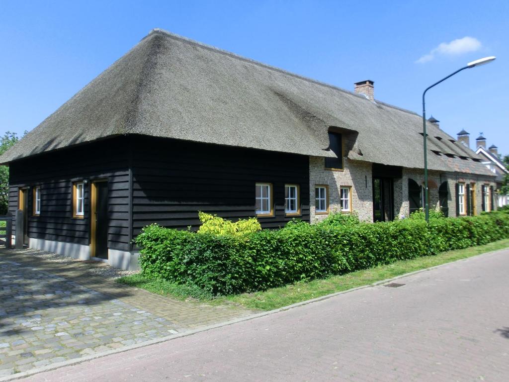 uma casa preta com telhado de palha numa rua em Boerderij & Bakhuis em Liempde