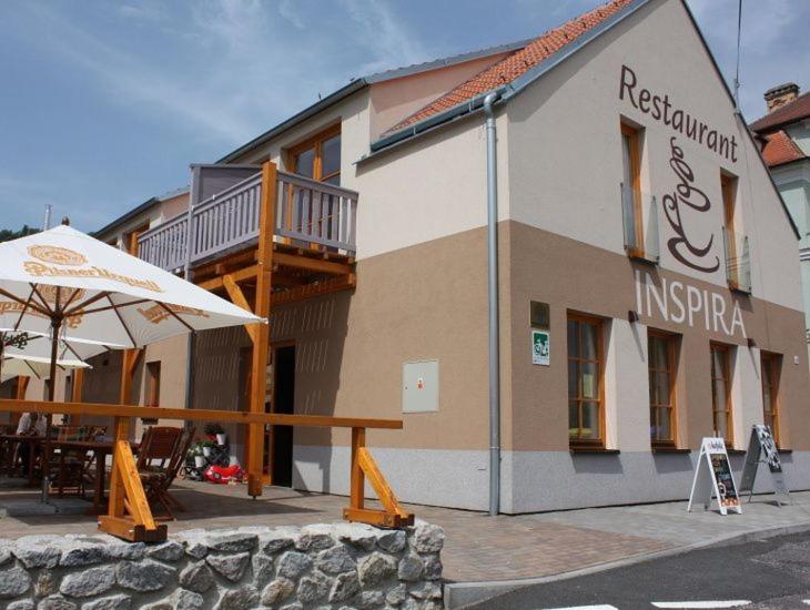 un bâtiment avec une table et un parasol devant lui dans l'établissement Penzion INspira, à Vranov nad Dyjí