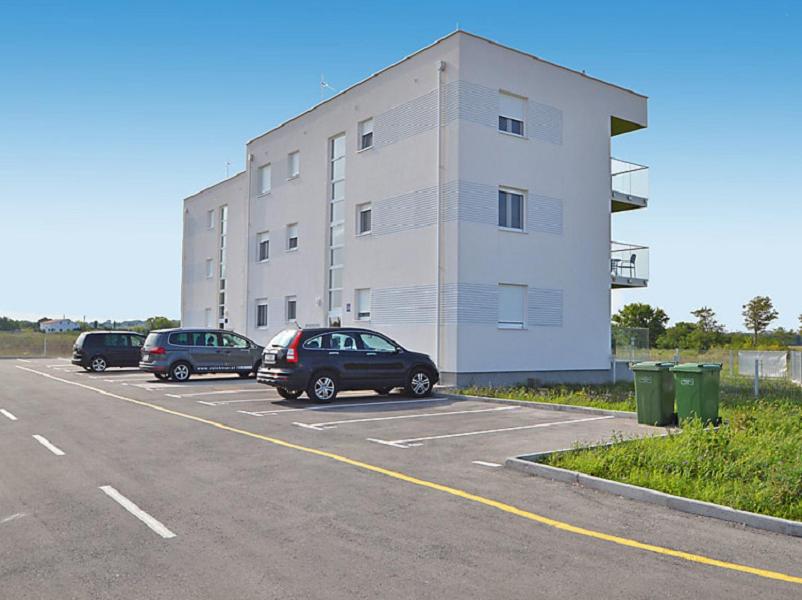 um parque de estacionamento com carros estacionados em frente a um edifício em Apartments Juhart em Nin