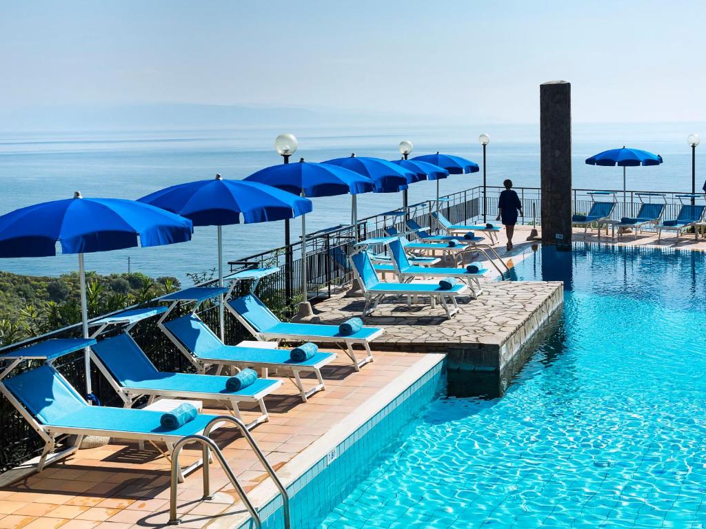 a row of blue chairs and umbrellas in a swimming pool at Hotel Sirius in Taormina