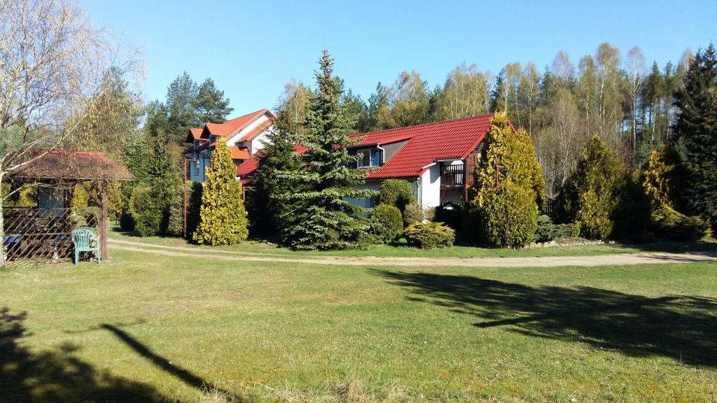ein Haus mit rotem Dach im Hof in der Unterkunft Agroturystyka Pod Klonem in Funkelkau