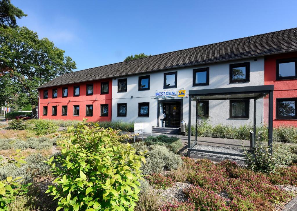 a red and white building with plants in front of it at Best Deal Airporthotel Weeze in Weeze