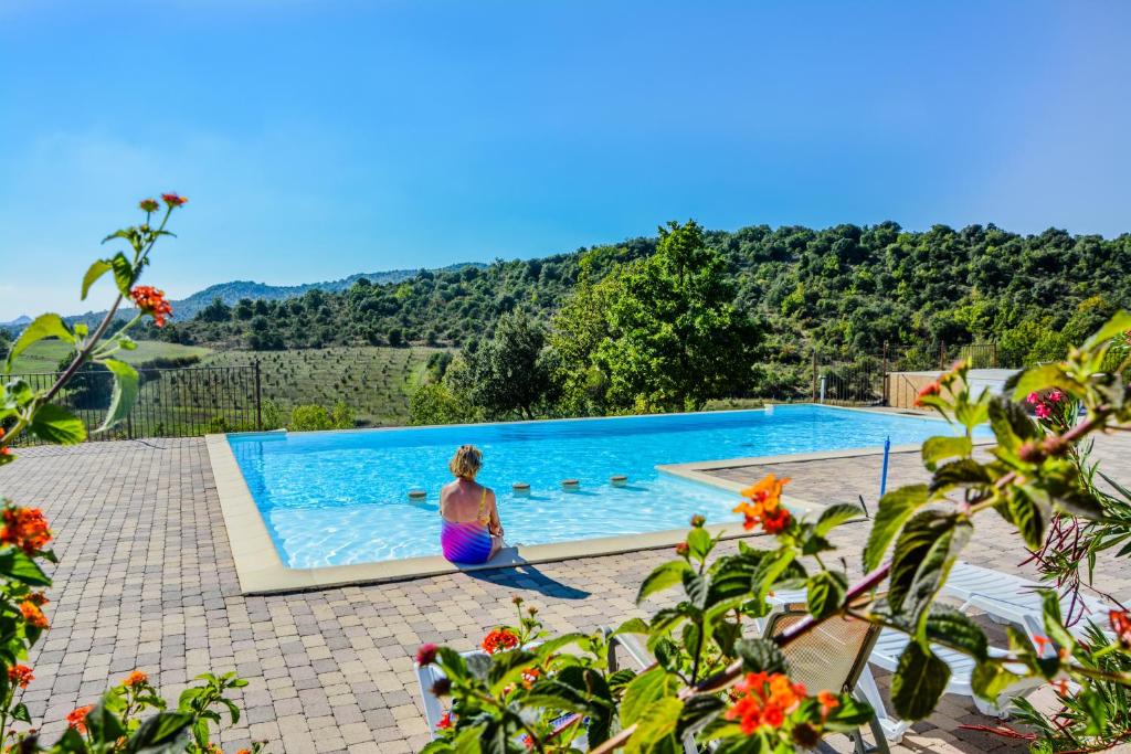 a woman standing in front of a swimming pool at Domaine de Chadeyron in Lagorce