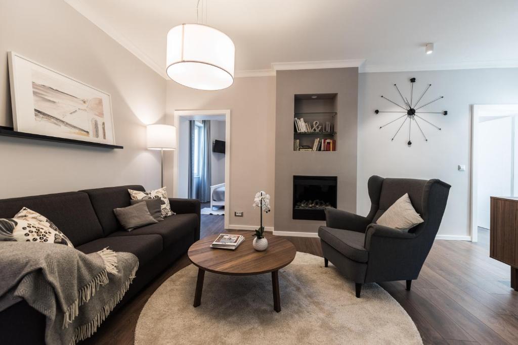 a living room with a couch and chairs and a clock at Sunset Beach Apartment in Zadar