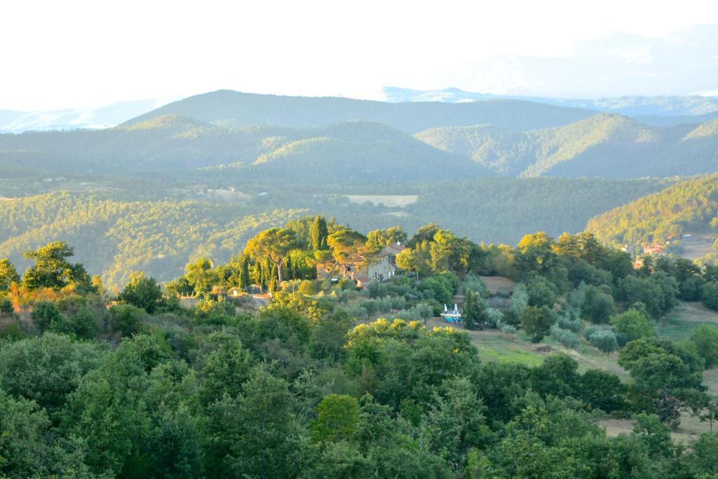 a house on a hill with mountains in the background at Relais Il Pozzeto in Anghiari