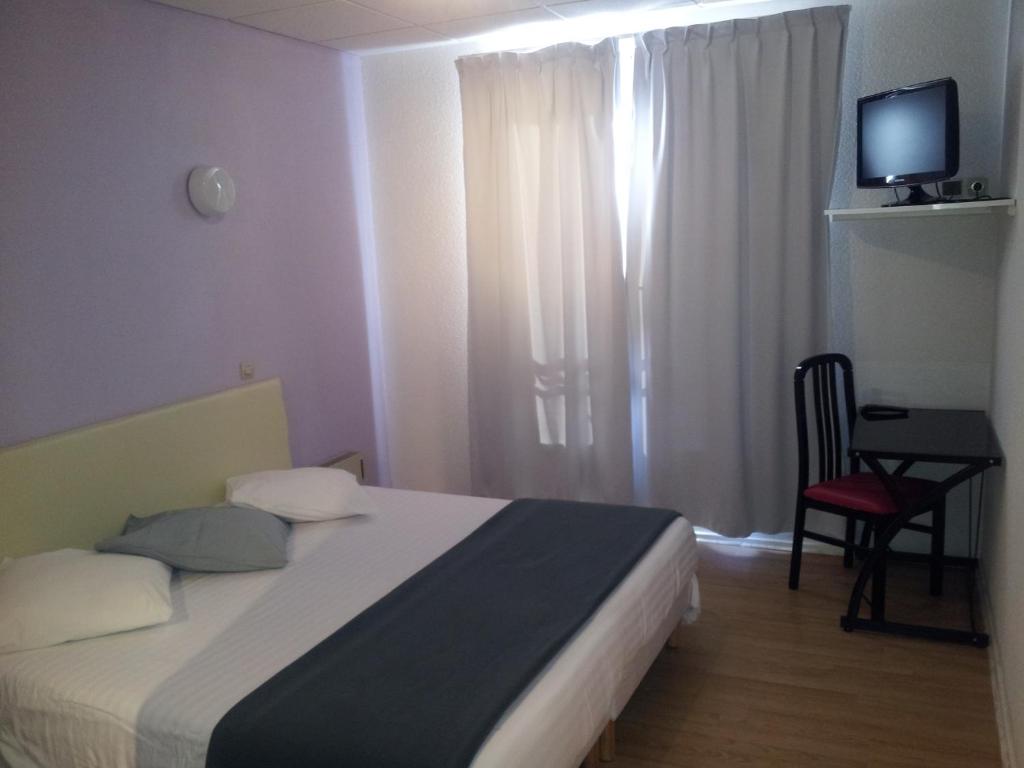 Schlafzimmer mit einem Bett, einem Tisch und einem TV in der Unterkunft Le Clos Fleuri in Bourg-de-Thizy