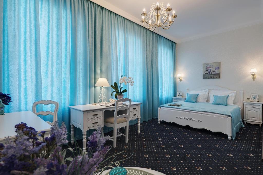 een slaapkamer met blauwe gordijnen, een bureau en een bed bij Gostiny Dvor Hotel in Charkov