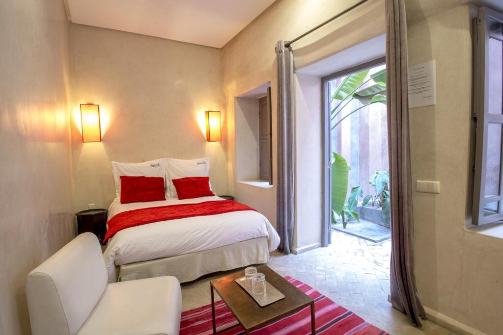sypialnia z łóżkiem z czerwonymi poduszkami i oknem w obiekcie Riad Vendôme & Spa w Marakeszu