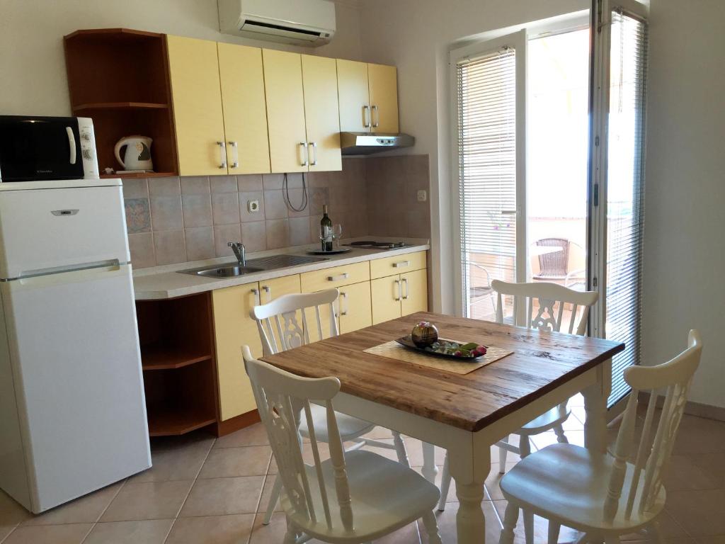 a kitchen with a table and chairs and a white refrigerator at Apartmani Lorena in Privlaka