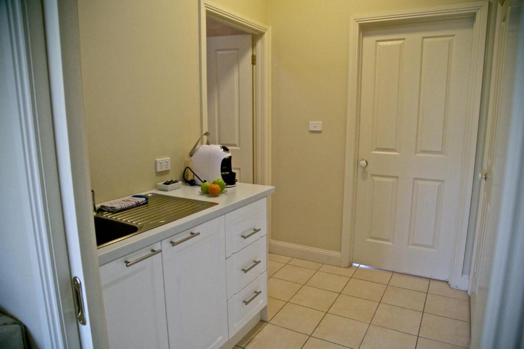 uma cozinha com armários brancos e uma bancada em Holly Lane Mews em Yarra Glen