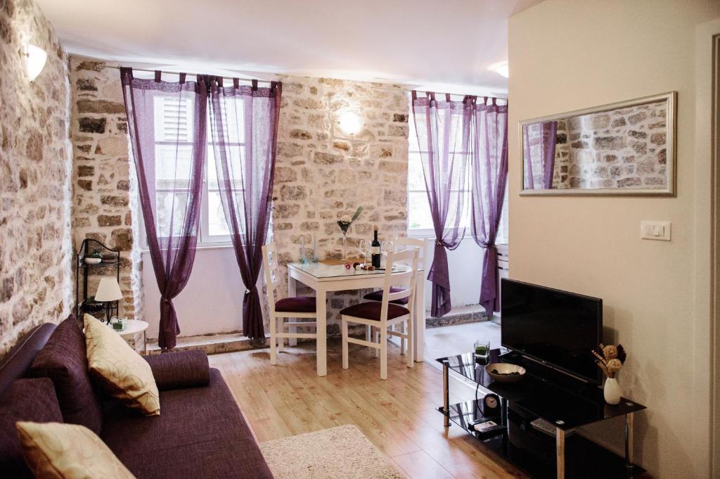 een woonkamer met paarse gordijnen, een tafel en een bank bij Apartment Peristil Cardo in Split