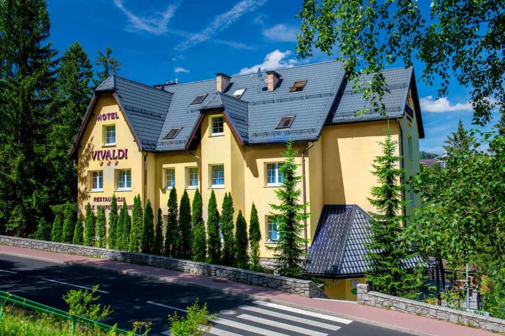 a yellow building with a black roof at Hotel Vivaldi in Karpacz
