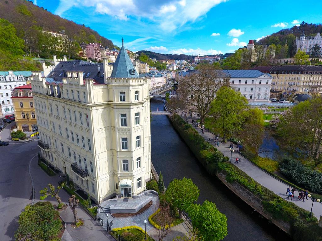 a white building next to a river in a city at Hotel Pavlov in Karlovy Vary