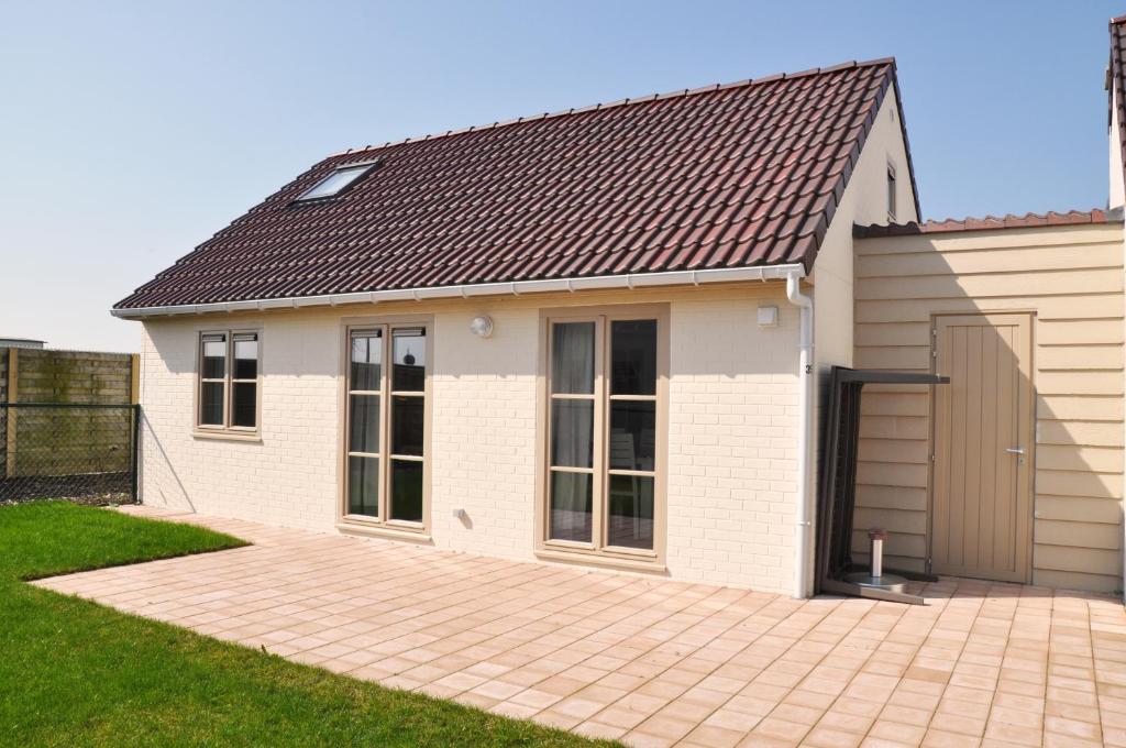 une petite maison blanche avec un toit marron dans l'établissement Zeepark Mercator, à Wenduine