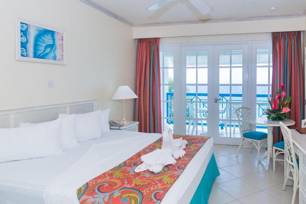 a bedroom with a bed and a balcony with the ocean at Rostrevor Hotel in Christ Church