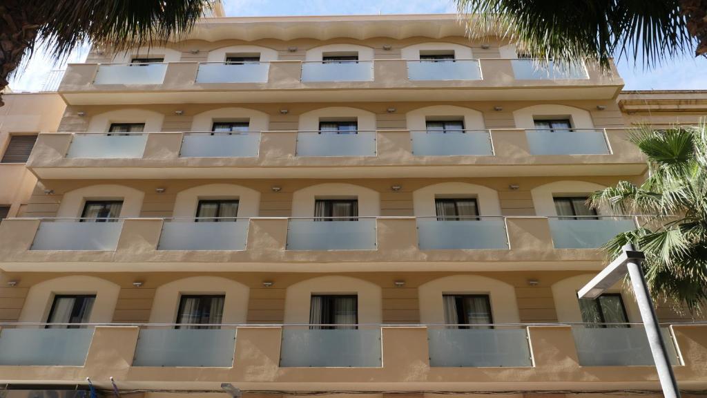 an apartment building with balconies and palm trees at Hotel Rusadir in Melilla