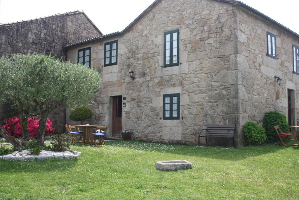 um edifício de pedra com uma mesa e cadeiras num quintal em A Casa da Meixida em Padrón