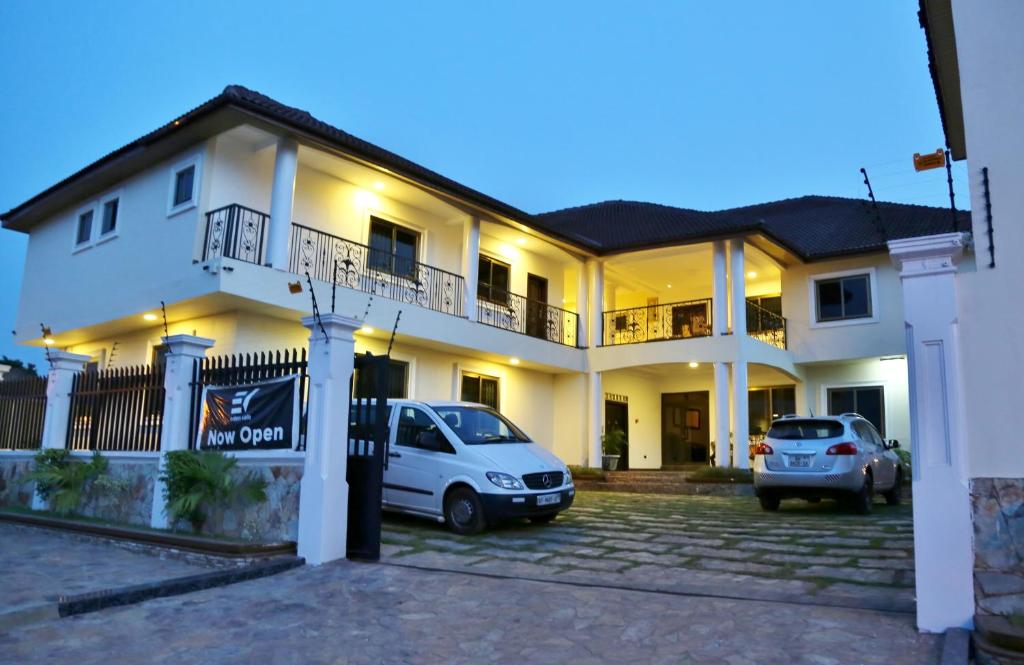 a white house with cars parked in a parking lot at Eden Vale Hotel in Ajiringano