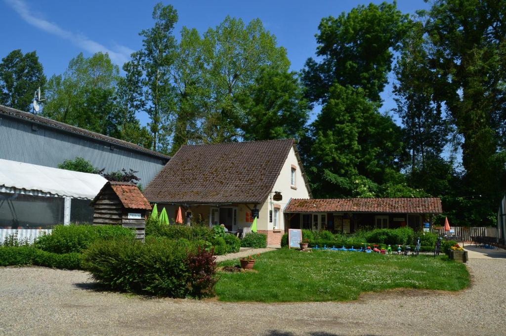 une petite maison blanche avec des toits bruns dans une cour dans l'établissement Camping Le Val de Trie, à Béhen