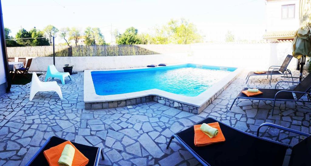 a swimming pool with two chairs and a table at Guest House Ilic in Loborika