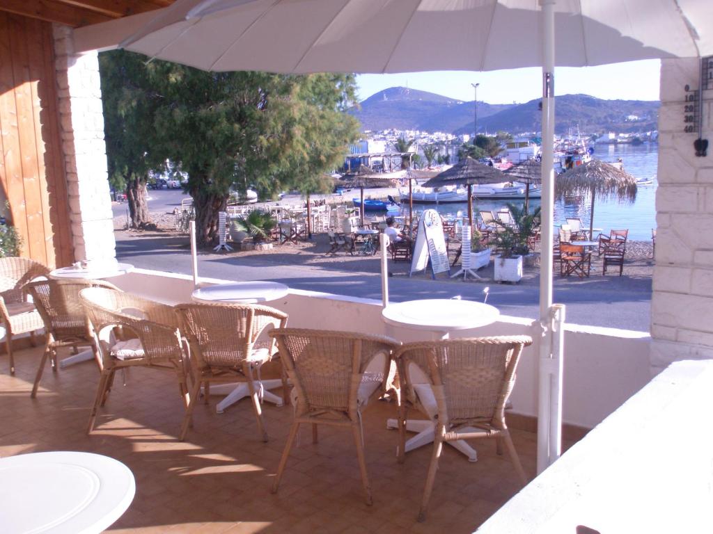 uma mesa com cadeiras e um guarda-sol num pátio em Captain's House Hotel em Skala