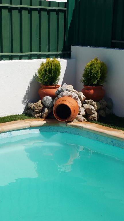 a swimming pool with two potted plants next to a fence at Arrabida´s Sweet Home in Azeitao