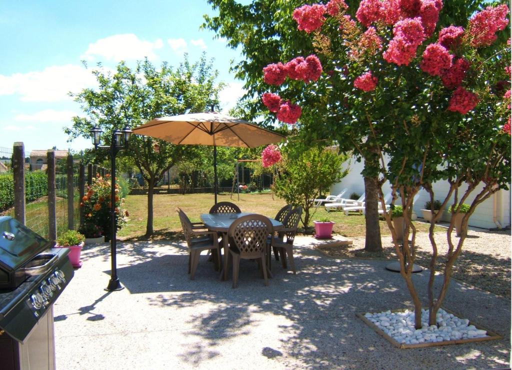 a table and chairs under an umbrella in a garden at Gîte L'Hirondelle in Castelnau-de-Médoc