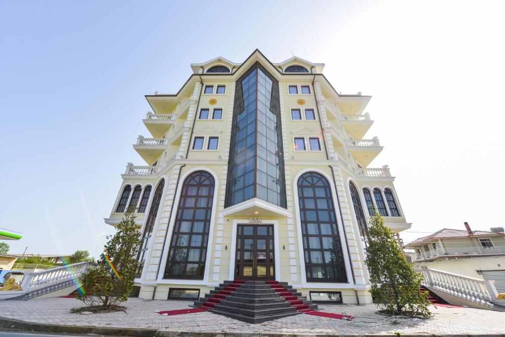 un edificio alto de color amarillo con una escalera delante en Luani ARTE en Shkodër