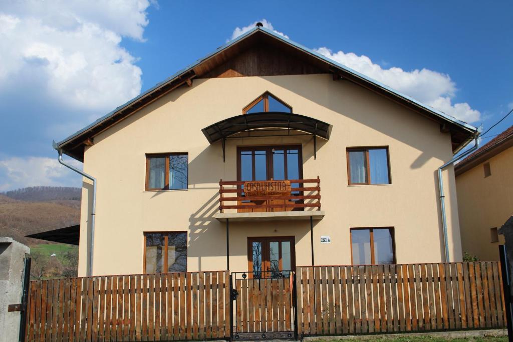 a house with a wooden fence in front of it at Casa Linistita in Chişcău