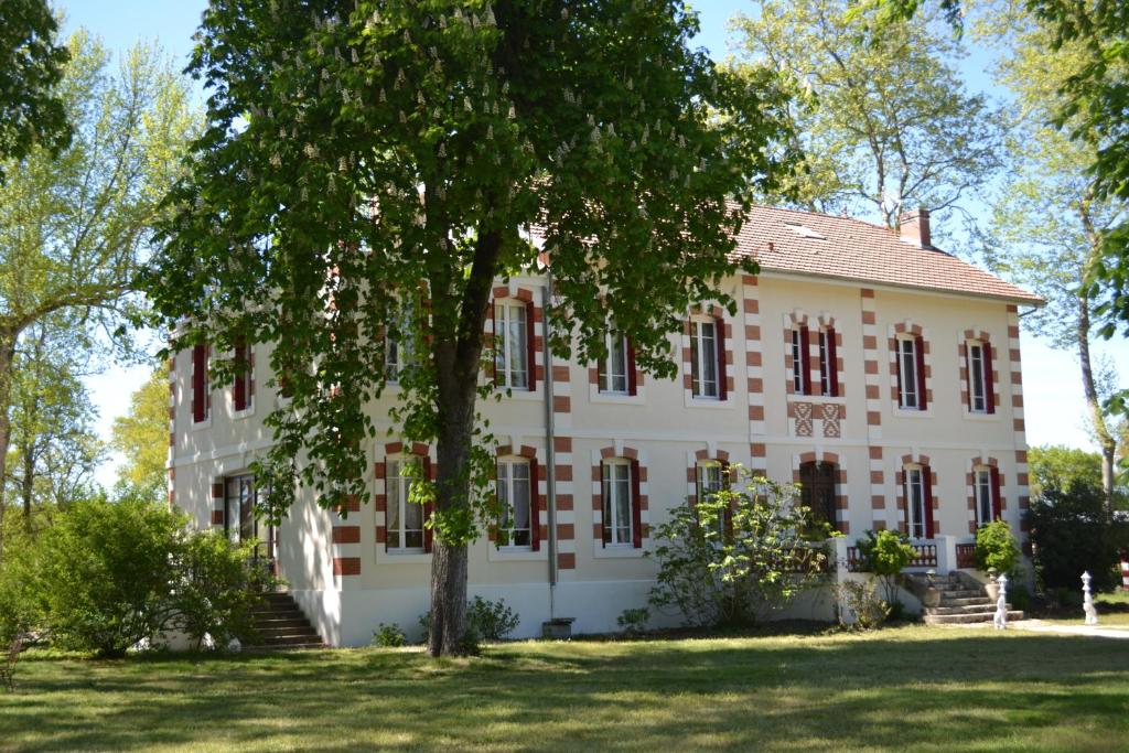 een oud gebouw met een boom ervoor bij Chambres d'hôtes le Domaine de Lugazaut in Vielle-Soubiran