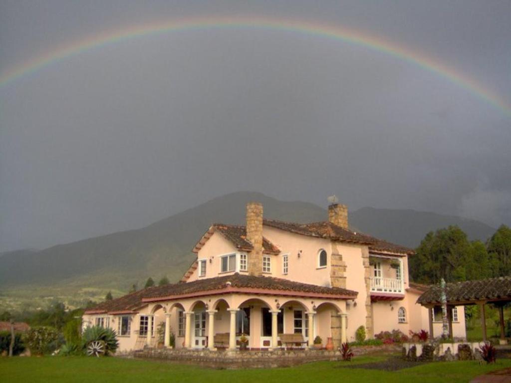 a rainbow over a large house with at Hacienda El Pinar del Viento in Villa de Leyva