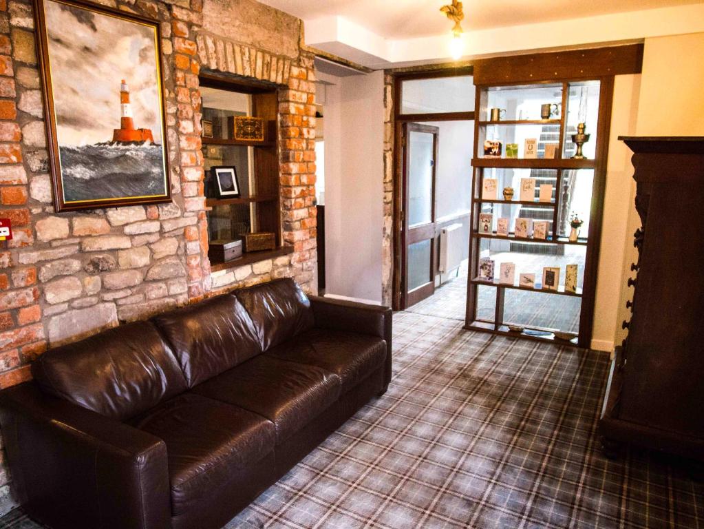 um sofá de couro num quarto com uma parede de tijolos em Longstone House Bed & Breakfast em Seahouses