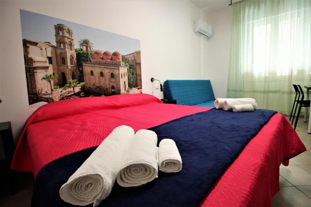 パレルモにあるInto Palermo B&Bのベッドルーム1室(赤と青のベッド1台、タオル付)
