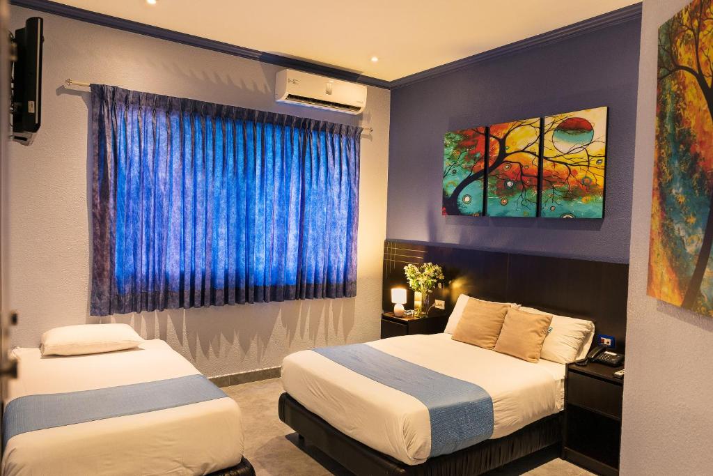 a hotel room with two beds and a window at Hotel Del Centro in Guayaquil
