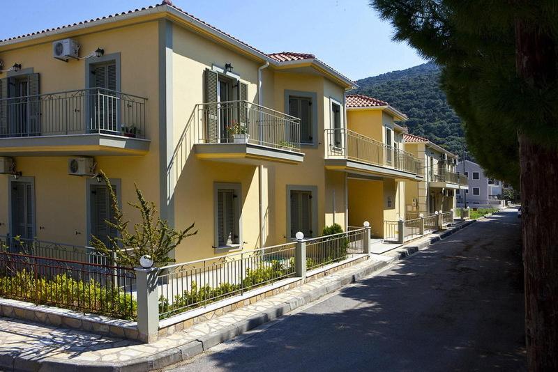 - un bâtiment jaune avec balcon dans une rue dans l'établissement Evangelia, à Agia Effimia