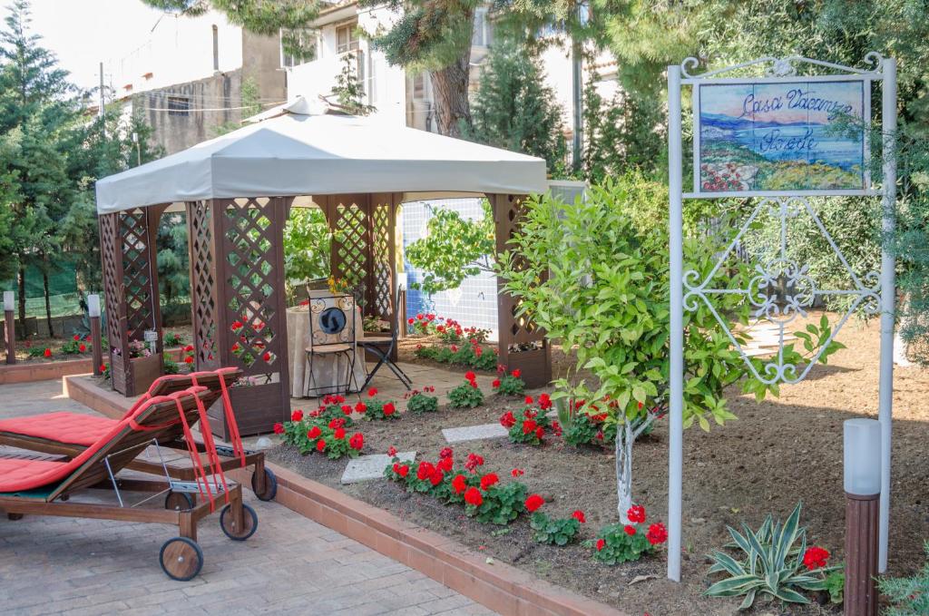 un giardino con ombrellone e carro rosso di Casa Vacanze "Ro & Se" a Palinuro IT, Bandiera Blu anche per il 2024 a Palinuro