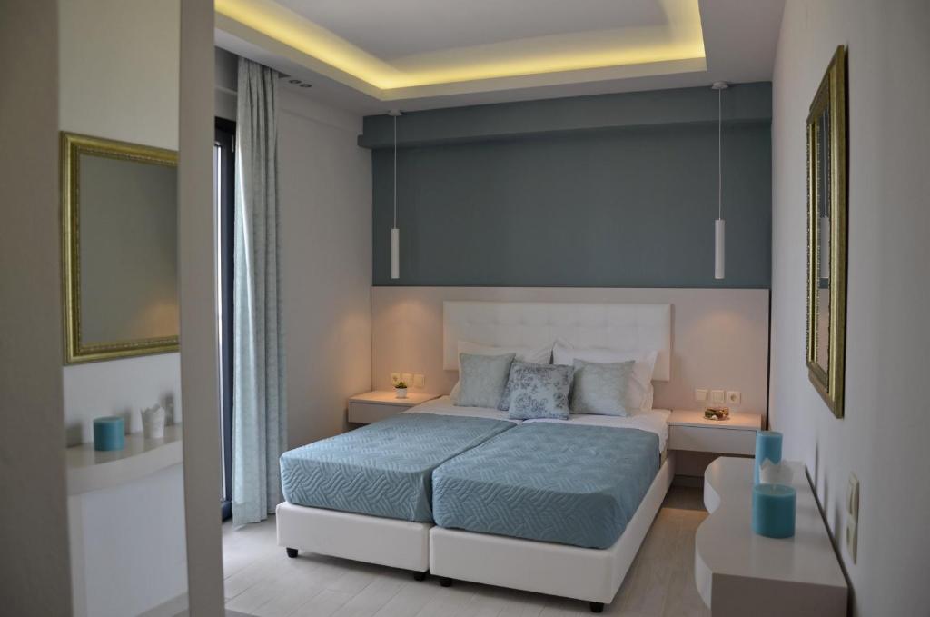 ein Schlafzimmer mit einem großen Bett mit blauer Bettwäsche und 2 Tischen in der Unterkunft Levante Sea View Studios in Stalida