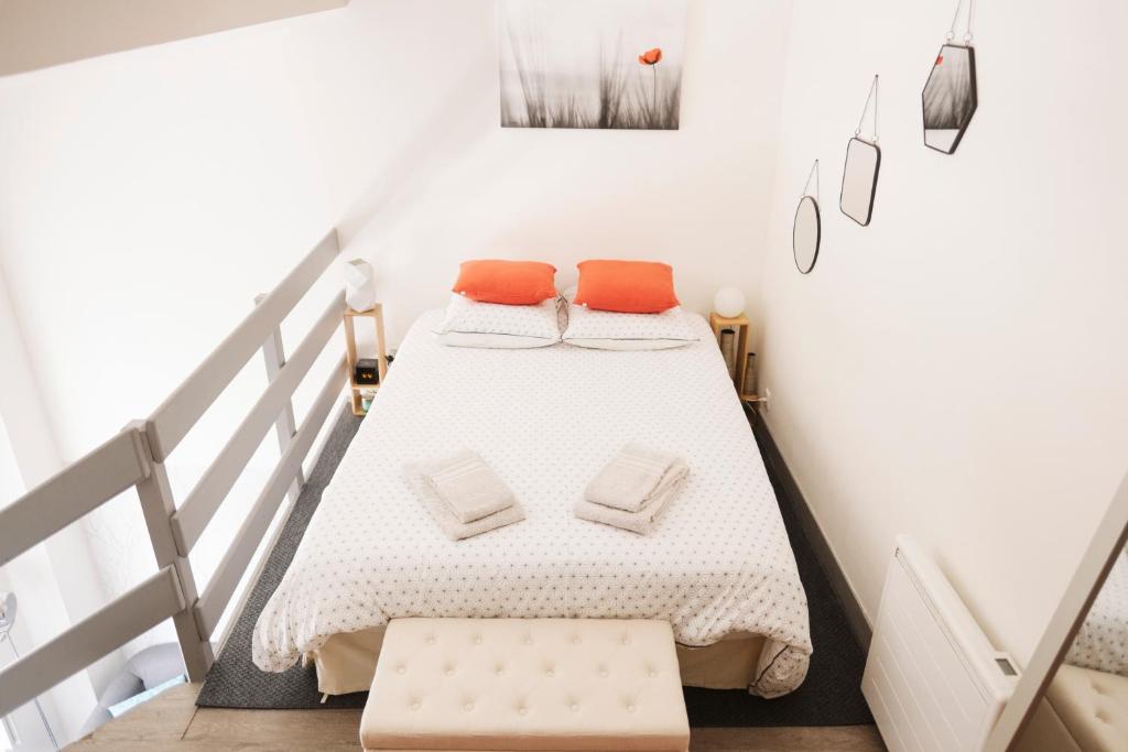 1 dormitorio con 1 cama con almohadas de color naranja en La Suite aquitaine, en Burdeos
