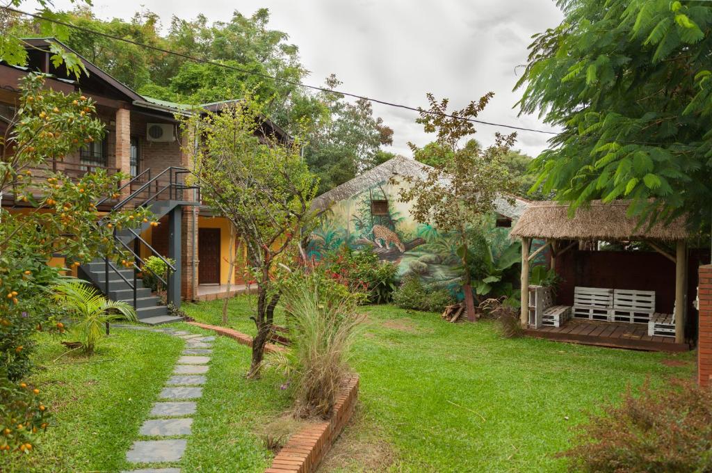 uma casa com um jardim de relva com uma casa em Hospedaje Los Vencejos em Puerto Iguazú