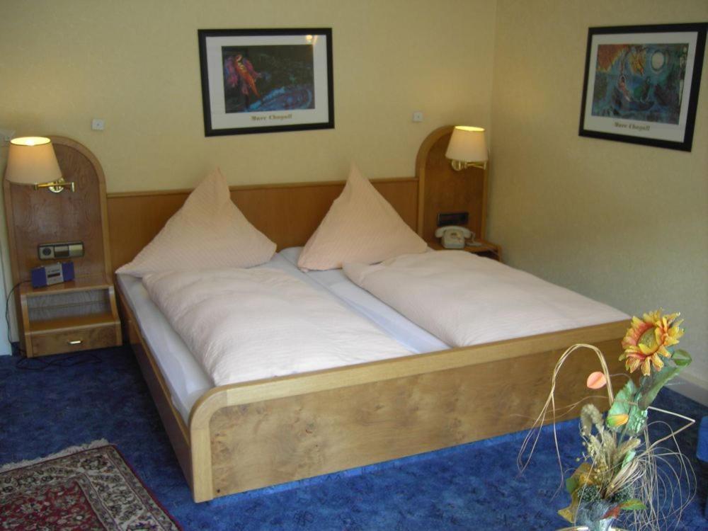 un letto con lenzuola e cuscini bianchi in una stanza di Hotel Traube a Bad Wildbad