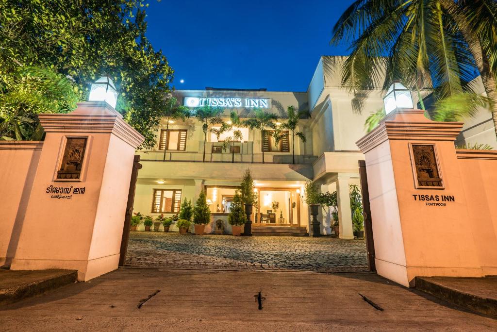 a large white building with two gates in front of it at Tissa's Inn in Cochin