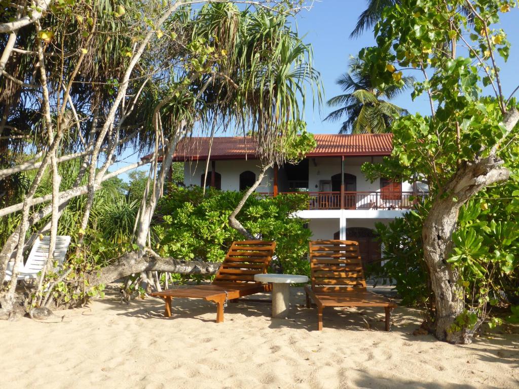 two chairs and a table on the beach in front of a house at Villa Sunrise in Tangalle