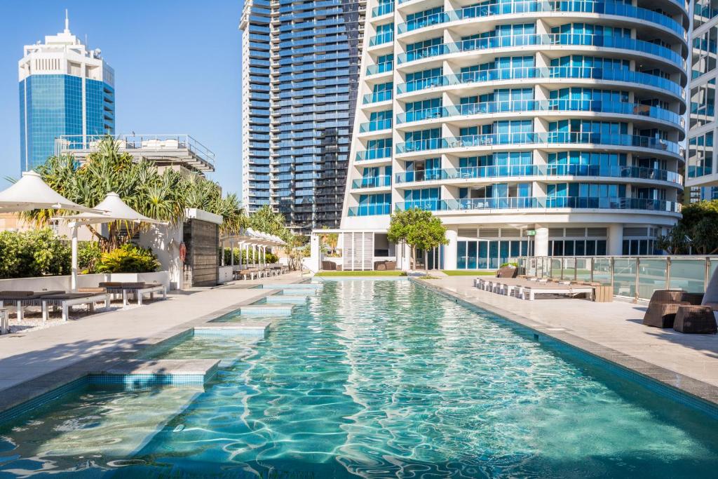 a swimming pool in front of a tall building at Holiday Holiday H-Residences Apartments in Gold Coast