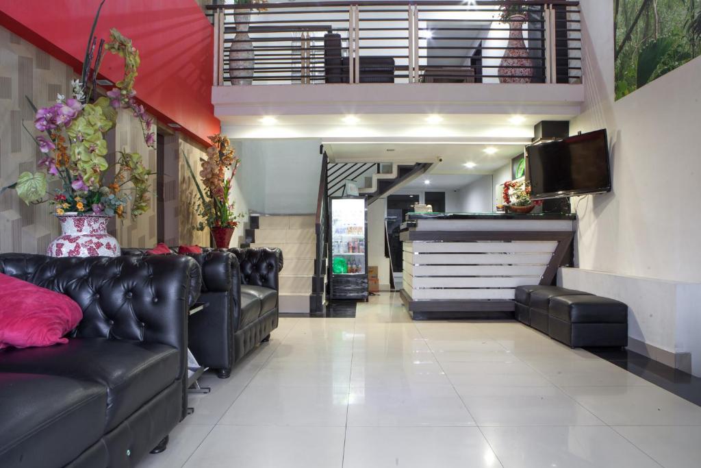 una sala d'attesa con divani in pelle nera e una hall di RedDoorz near Gedung Sate 2 a Bandung