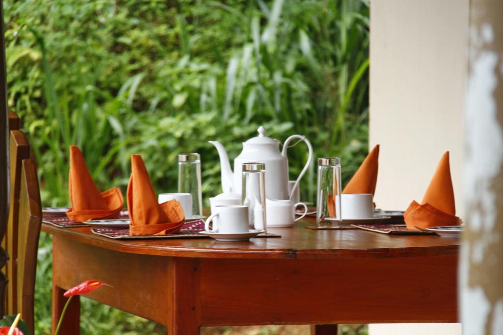 un tavolo con tovaglioli e tazze e un bollitore per il tè di Sinharaja Hostel 114 a Deniyaya