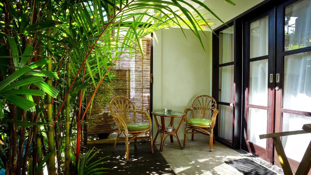 a patio with chairs and a table and some plants at Kembali Lagi Guest House in Sanur